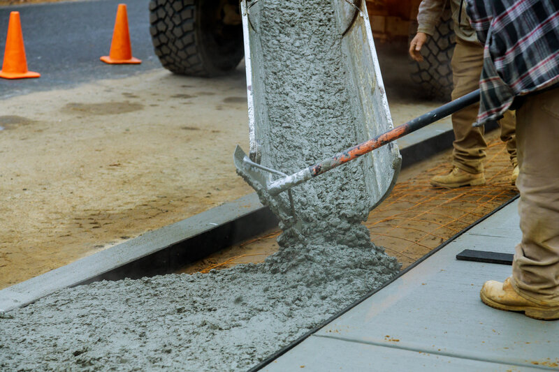 Fresh concrete being poured or finished — smooth wet surface with forms visible. Worker with float or trowel.