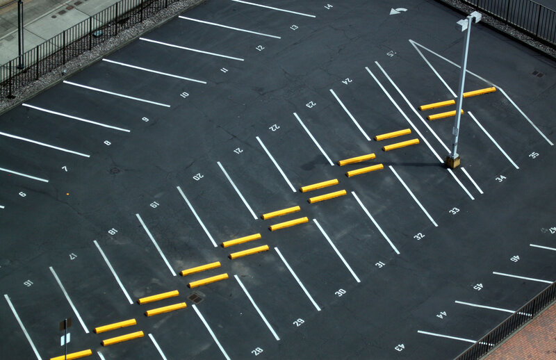 Freshly striped parking lot with numbered spaces and yellow bollards